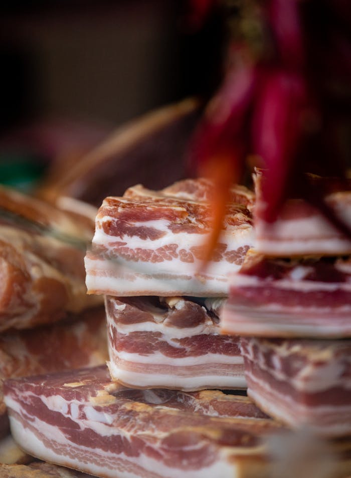 A heap of stacked raw bacon slices, showcasing intricate marbling and texture.
