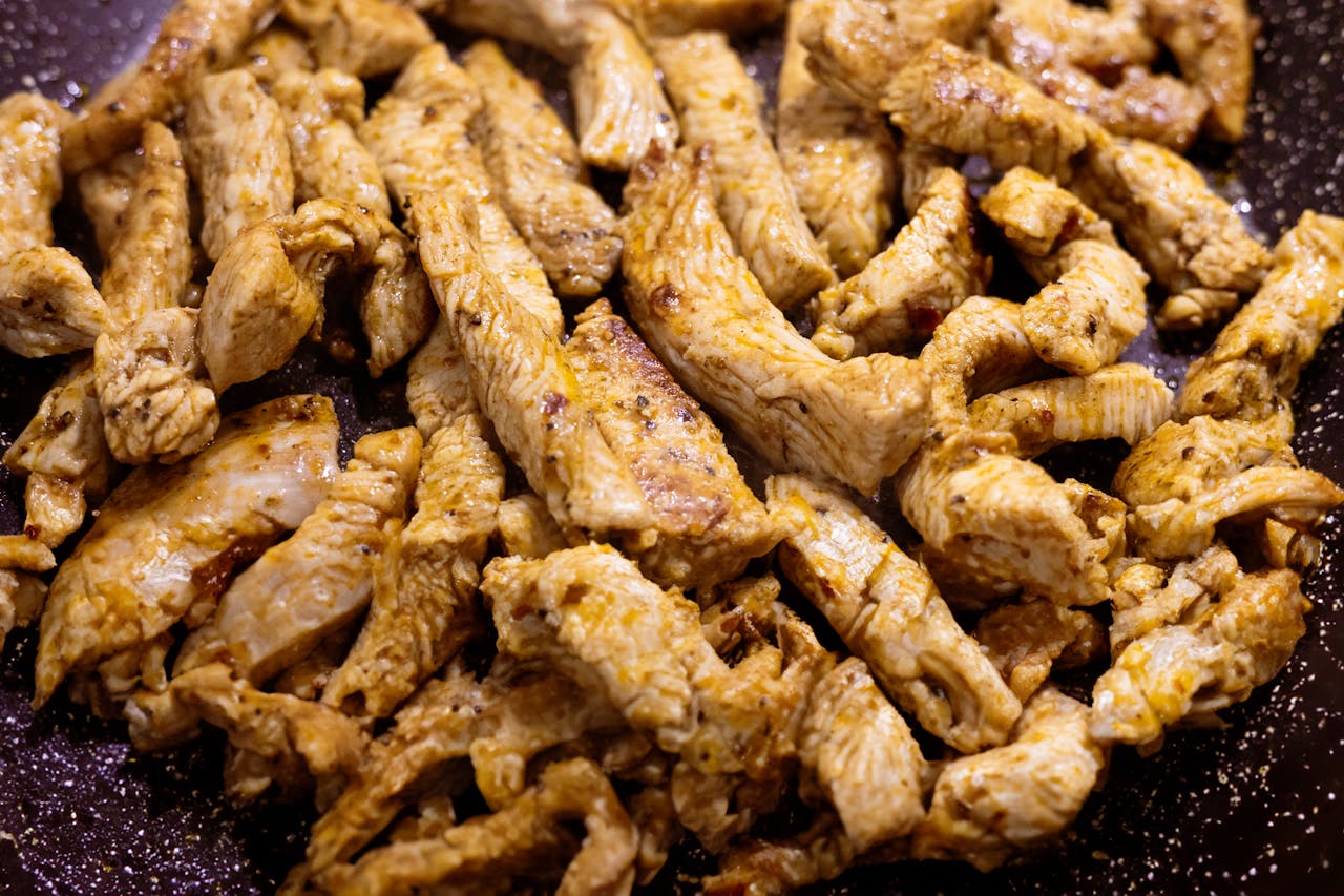 Deliciously cooked chicken strips in a non-stick pan, perfect for a healthy meal.